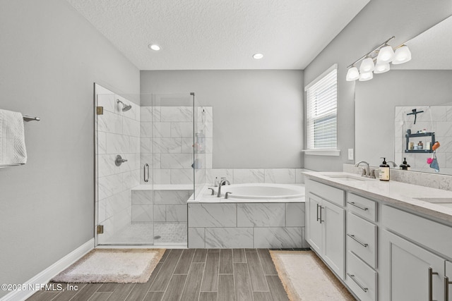 full bathroom featuring a garden tub, a textured ceiling, wood finish floors, a shower stall, and a sink