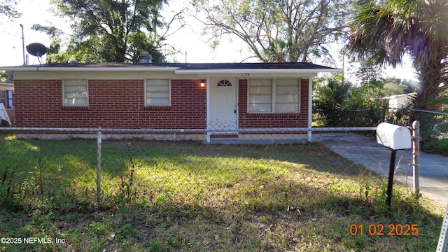 view of front facade featuring a fenced front yard, a front lawn, and brick siding