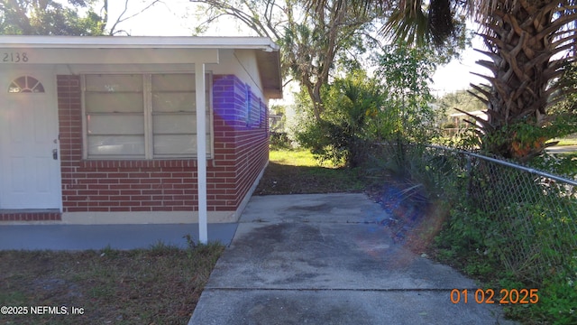 view of property exterior with fence and brick siding