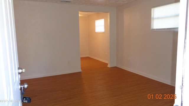 unfurnished room featuring wood finished floors, visible vents, and baseboards