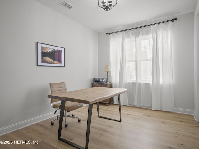 office with light wood-style flooring, visible vents, and baseboards