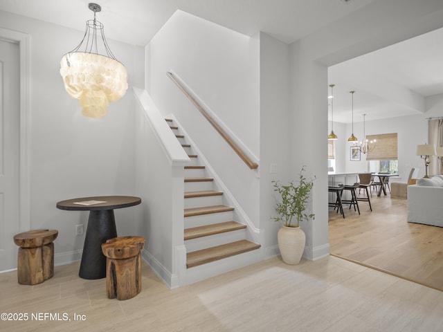 stairs with a notable chandelier, baseboards, and wood finished floors