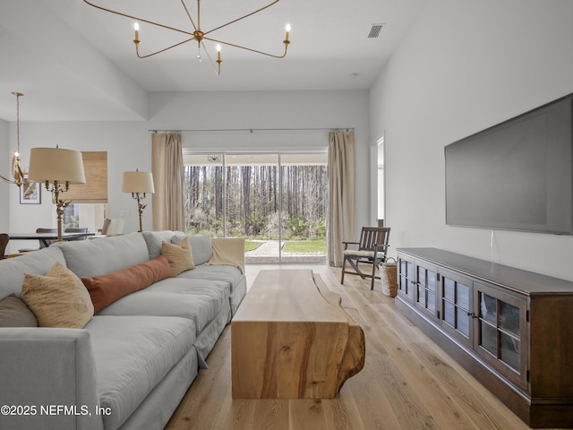 living room featuring an inviting chandelier, visible vents, and wood finished floors