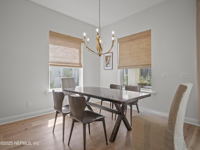 dining room featuring a chandelier, baseboards, and light wood finished floors