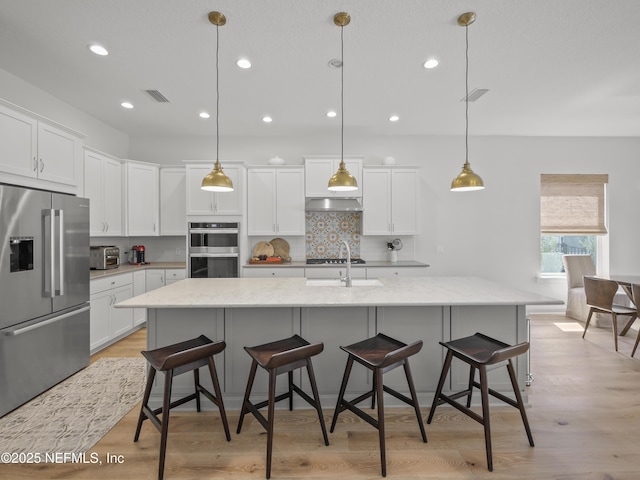 kitchen featuring appliances with stainless steel finishes, white cabinetry, visible vents, and tasteful backsplash