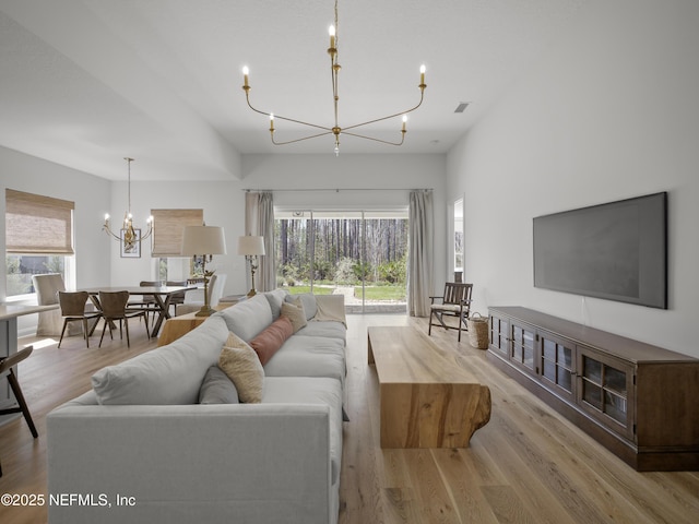 living room with an inviting chandelier, visible vents, and wood finished floors