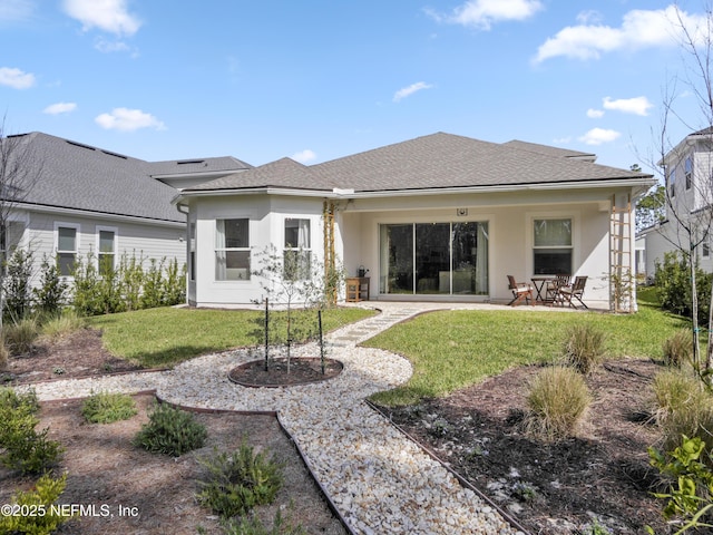 back of house with a yard, a patio, a shingled roof, and stucco siding