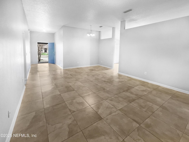 spare room with baseboards, visible vents, a chandelier, and a textured ceiling