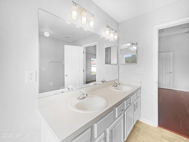 bathroom featuring double vanity, toilet, a sink, and tile patterned floors