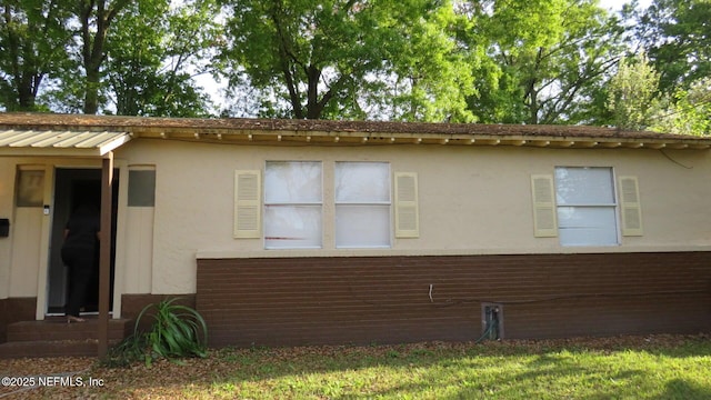 view of property exterior with brick siding, metal roof, and stucco siding