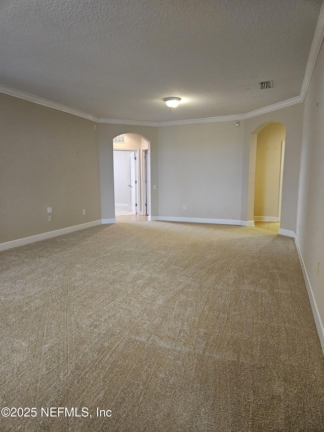 unfurnished room with visible vents, arched walkways, baseboards, ornamental molding, and carpet