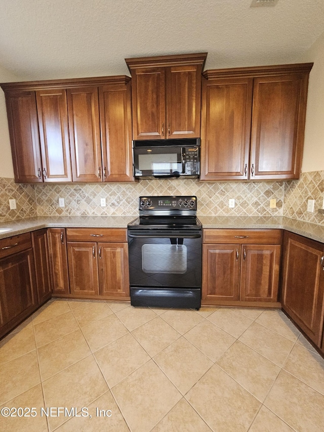 kitchen featuring black appliances, light tile patterned floors, decorative backsplash, and brown cabinetry