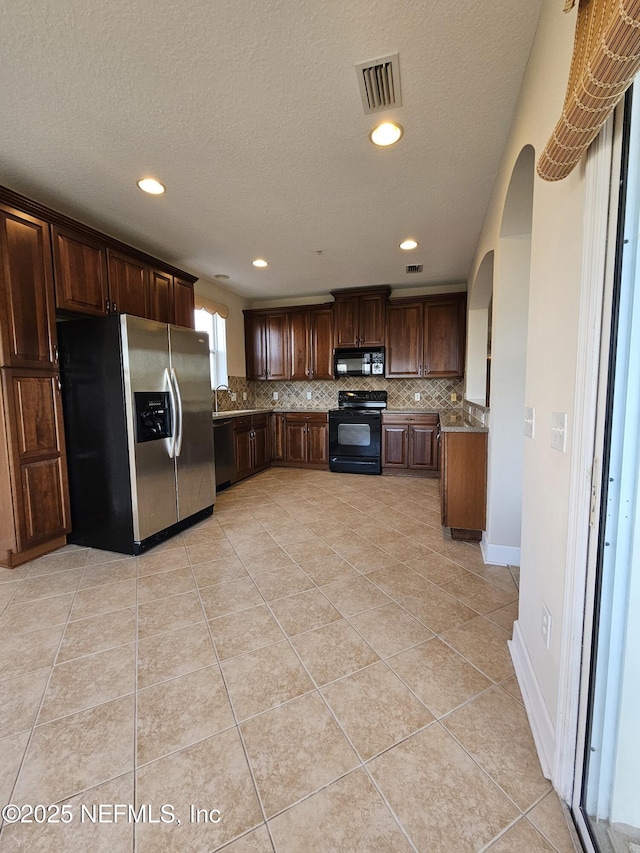 kitchen with visible vents, backsplash, black appliances, and light tile patterned flooring