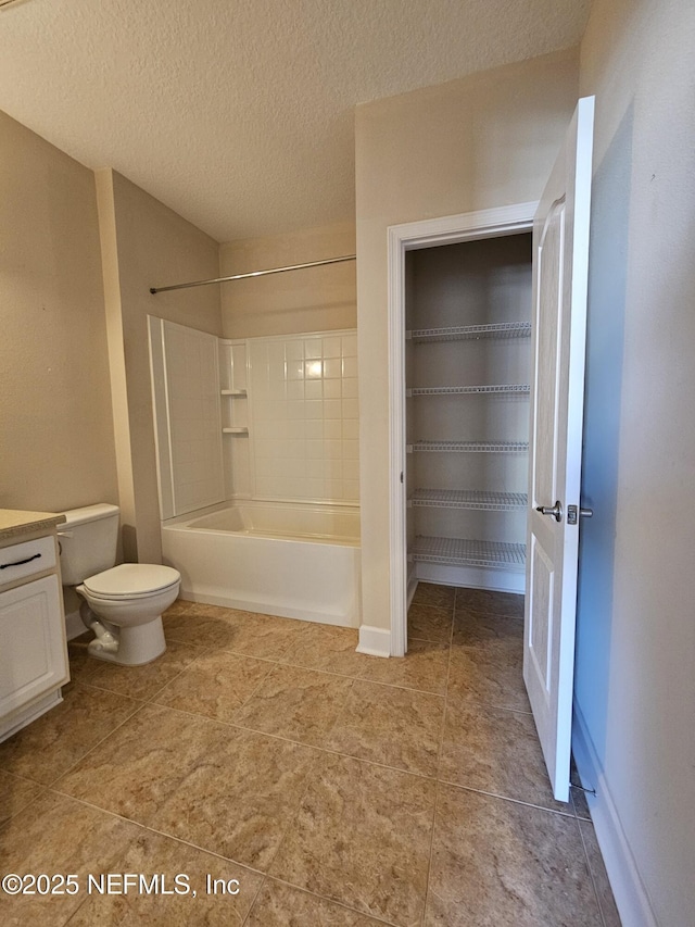 full bathroom with a textured ceiling, tile patterned flooring, toilet, vanity, and washtub / shower combination