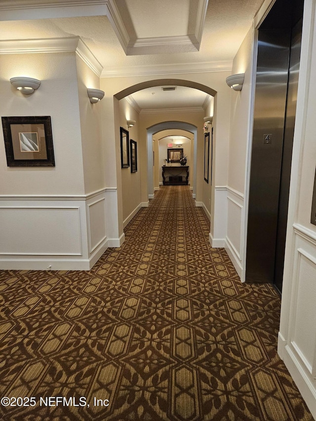 hallway with arched walkways, a decorative wall, and wainscoting