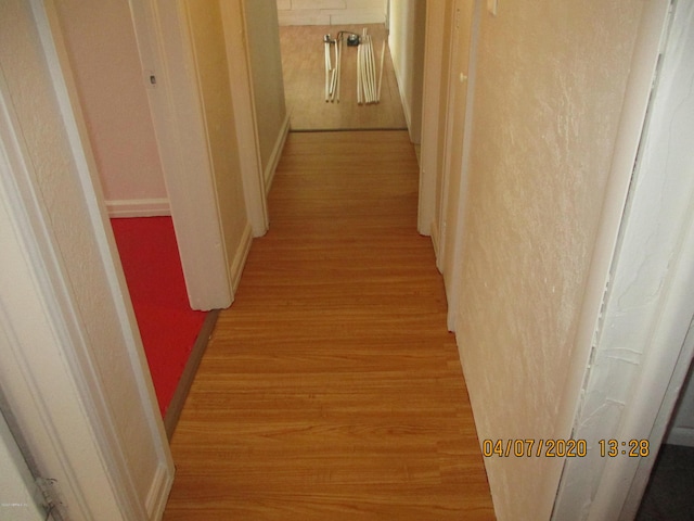 hallway featuring light wood-style floors and baseboards