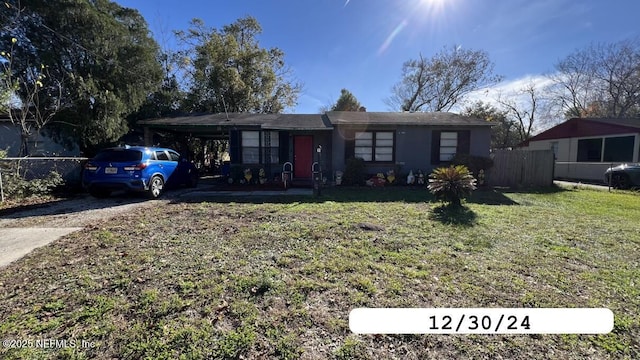 ranch-style home featuring driveway, a front lawn, fence, and an attached carport