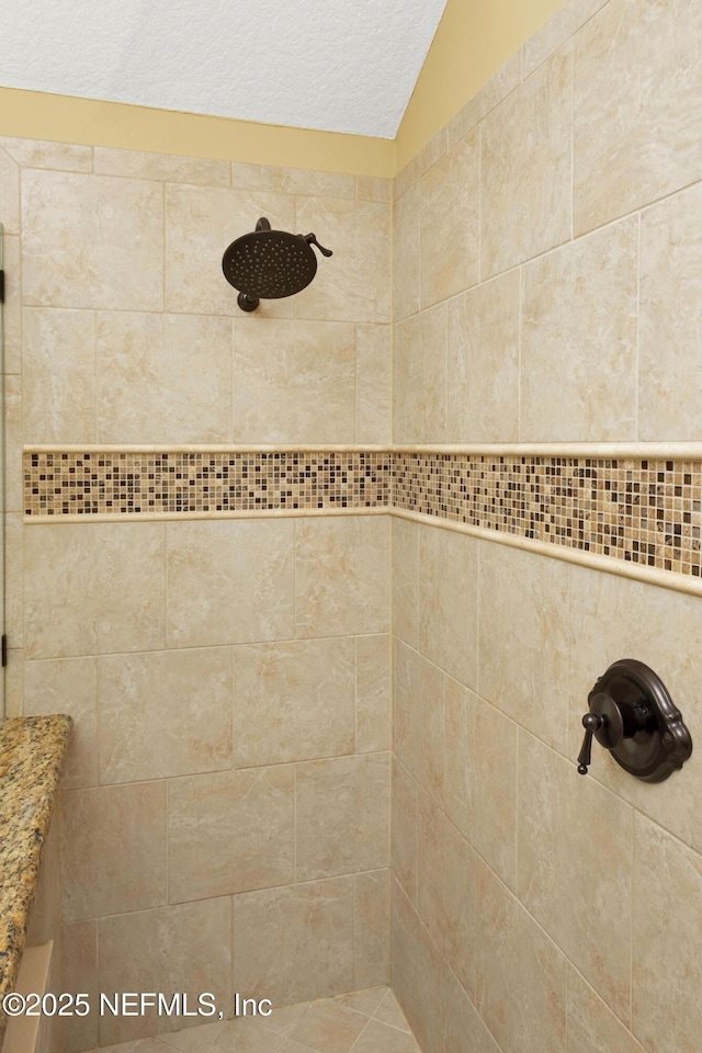 bathroom featuring vaulted ceiling and a tile shower