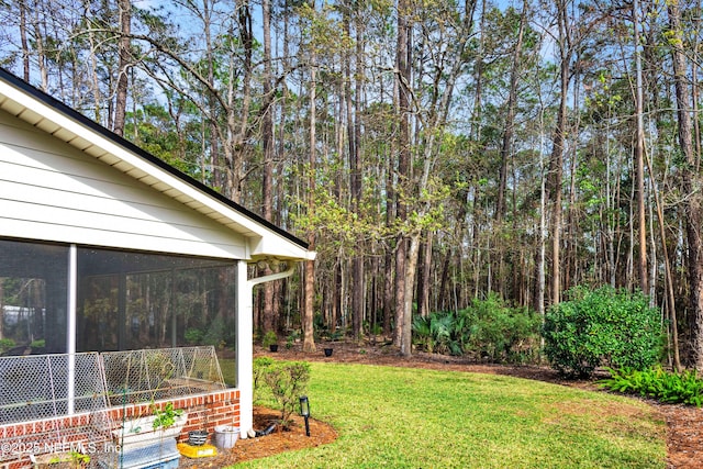 view of yard featuring a sunroom and a view of trees