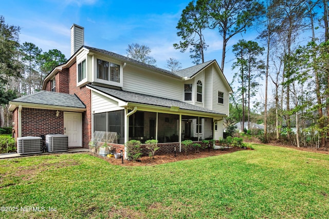 rear view of house featuring a yard, a chimney, a sunroom, and central air condition unit