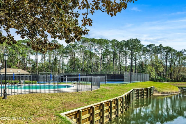 pool with a yard, a water view, and fence