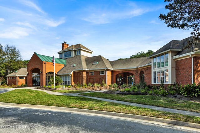 view of front of home featuring a chimney, a front lawn, and brick siding