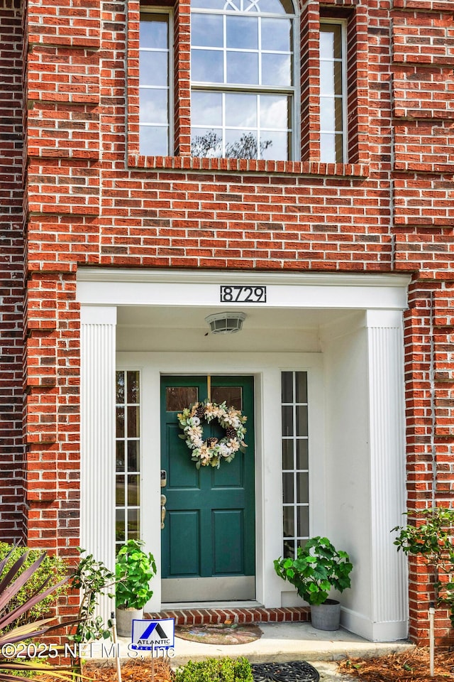 view of exterior entry featuring brick siding