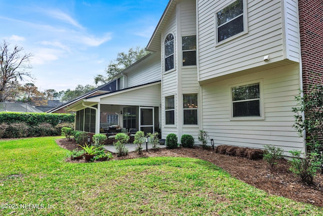 rear view of property with a sunroom, a patio, and a lawn