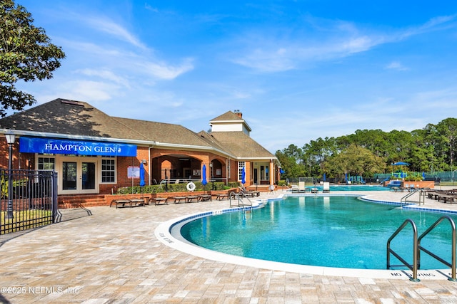 community pool featuring french doors, a patio area, and fence