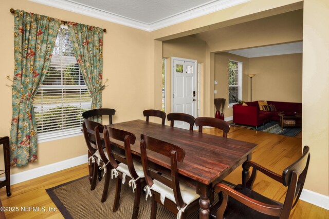 dining space with light wood-style floors, baseboards, and crown molding