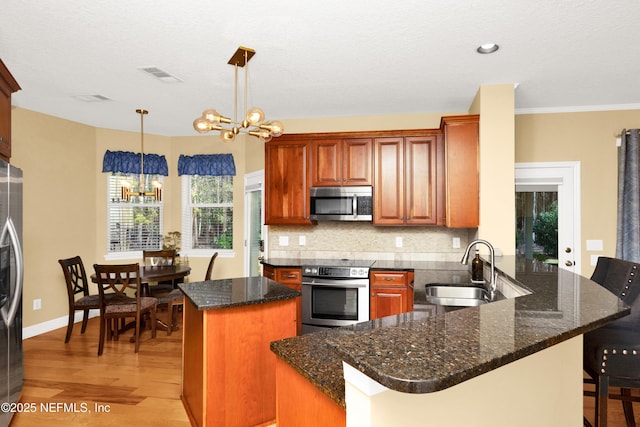 kitchen with a chandelier, a sink, visible vents, appliances with stainless steel finishes, and decorative backsplash