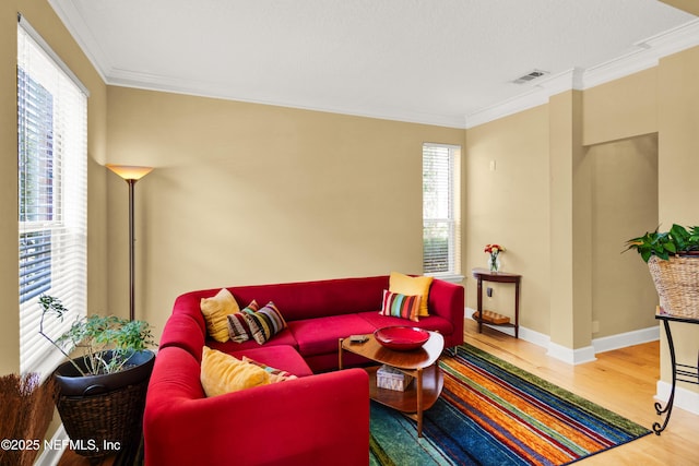 living area featuring visible vents, crown molding, baseboards, and wood finished floors