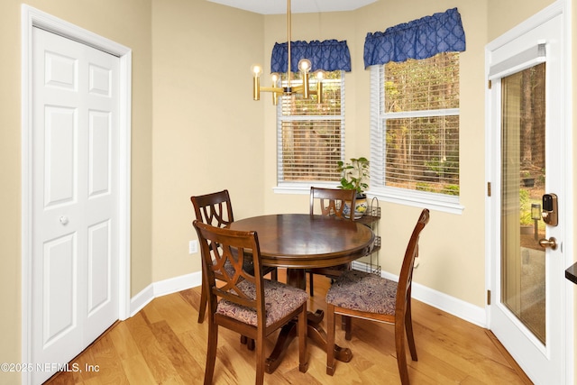 dining room featuring light wood-style flooring, baseboards, and a notable chandelier