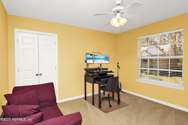 carpeted office space with a ceiling fan and baseboards