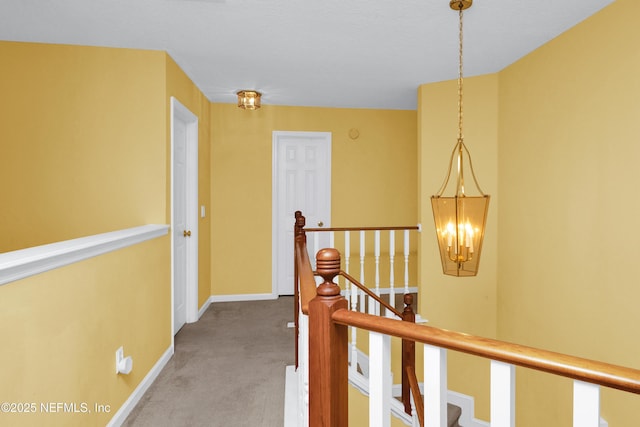 corridor featuring baseboards, an upstairs landing, and light colored carpet