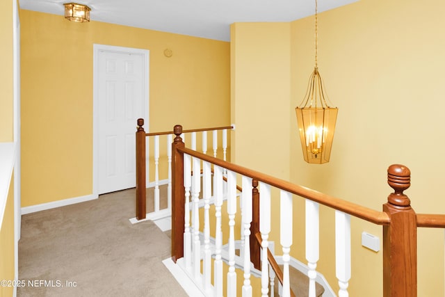 corridor with baseboards, carpet floors, an upstairs landing, and a notable chandelier