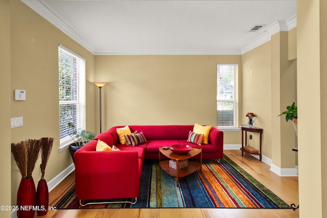 living room with a healthy amount of sunlight, visible vents, crown molding, and wood finished floors