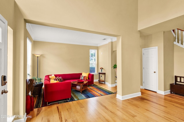 living area featuring stairs, ornamental molding, baseboards, and wood finished floors