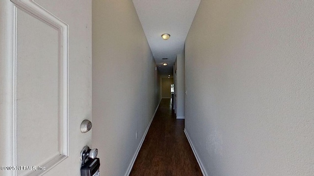 corridor with dark wood finished floors and baseboards