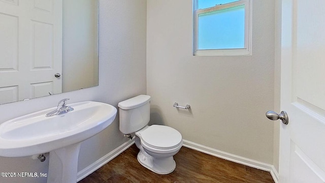 half bath with wood finished floors, toilet, and baseboards