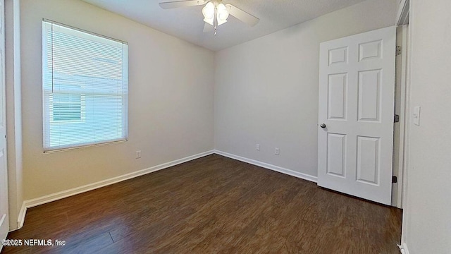 unfurnished room with baseboards, dark wood finished floors, and a ceiling fan