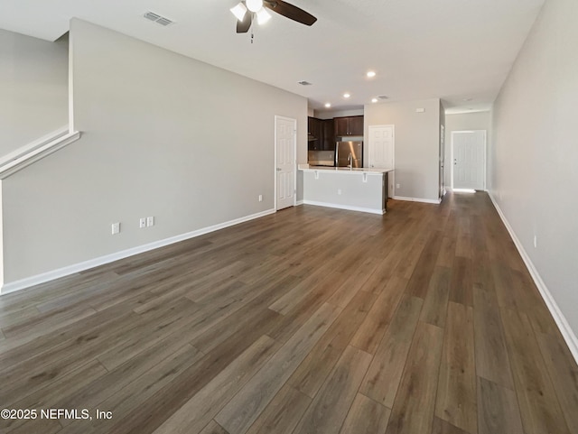 unfurnished living room with baseboards, visible vents, ceiling fan, dark wood-type flooring, and recessed lighting