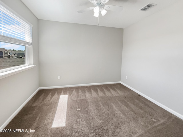 carpeted empty room with ceiling fan, visible vents, and baseboards