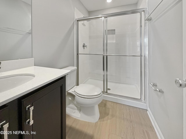 bathroom with toilet, a stall shower, wood finished floors, and vanity