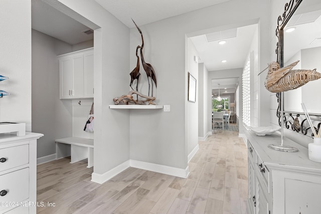 hallway with light wood-style floors, visible vents, and baseboards