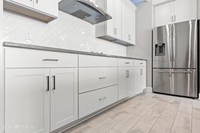 kitchen featuring range hood, white cabinetry, backsplash, and stainless steel fridge with ice dispenser