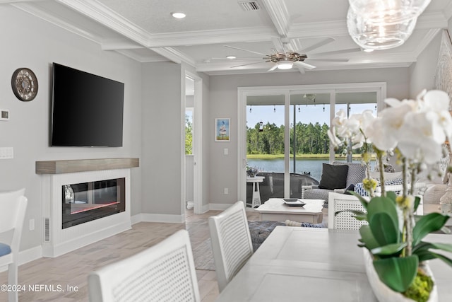 living area with ornamental molding, coffered ceiling, a glass covered fireplace, and beam ceiling