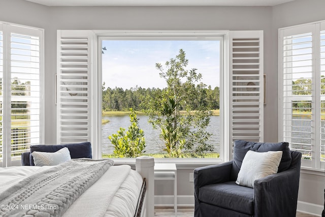 bedroom featuring multiple windows, a water view, and baseboards