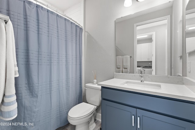 full bathroom with a textured wall, curtained shower, toilet, vanity, and washer and clothes dryer