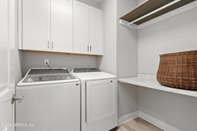 laundry area with baseboards, separate washer and dryer, cabinet space, and light wood-style floors